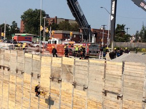 Firefighters lift a victim on a stretcher out of a 75-foot deep construction site on King Edward Friday. The worker suffered a back injury and was in stable condition at the scene.