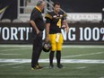 New Tiger-Cats head coach June Jones speaks with quarterback Zach Collaros (4), who was replaced as starter by Jeremiah Masoli, before Monday's home game against the Argonauts. THE CANADIAN PRESS/Peter Power