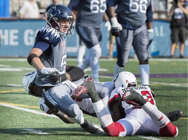 Montreal Alouettes quarterback Drew Willy, centre, is pulled down by Ottawa Redblacks' Avery Ellis, left, and Jonathan Newsome during second half CFL football action in Montreal, Sunday, September 17, 2017.