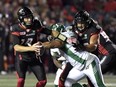 Redblacks quarterback Ryan Lindley (14) fends off Roughriders defensive lineman Eddie Steele during first-half play at TD Place stadium on Friday night. THE CANADIAN PRESS/Justin Tang
