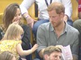 A toddler steals popcorn from Prince Harry.
