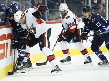 The Winnipeg Jets' Brendan Lemieux and the Ottawa Senators' Cody Ceci fight for possession as the Senators' Johnny Oduya and the Jets' Brandon Tanev look on.