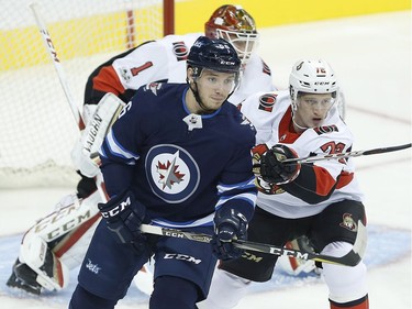 The Ottawa Senators' Thomas Chabot attempts to clear the Winnipeg Jets' Marko Dano as goaltender Mike Condon looks on.