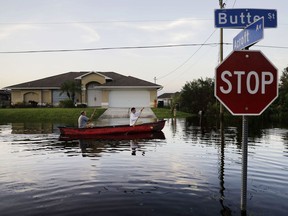 Pierre Ghantos, left, and his son, Nathan, paddle though their flooded neighbourhood in the aftermath of Hurricane Irma in Fort Myers, Fla. on Tuesday.