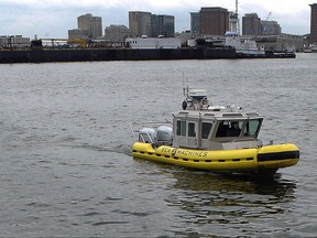 In this Tuesday, Aug. 15, 2017 photo, a boat capable of autonomous navigation makes its way around Boston Harbor. The experimental workboat spent this summer dodging tall ships and tankers, outfitted with sensors and self-navigating software and emblazoned with the words "UNMANNED VESSEL" across its aluminum hull. (AP Photo/Steven Senne)