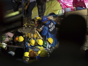 Search and rescue team members work to bring down a large piece of concrete during rescue efforts at the Enrique Rebsamen school in Mexico City, Mexico, Thursday, Sept. 21, 2017. A delicate effort to reach a young girl buried in the rubble of the school stretched into a new day on Thursday, a vigil broadcast across the nation as rescue workers struggled in rain and darkness to pick away unstable debris and reach her.