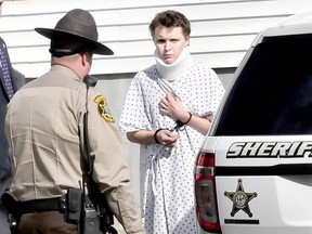 Wearing a hospital gown and neck brace, Zachary Wittke is led into a police transport vehicle following a 2013 arrest in Maine.