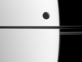 This May 21, 2015 image made available by NASA shows Saturn's moon Dione crossing the face of the gas giant, in a phenomenon astronomers call a transit