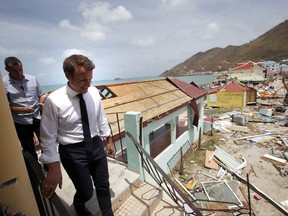FILE - This file photo dated Tuesday, Sept. 12, 2017, shows France's President Emmanuel Macron walking down a destroyed building during his visit in the French Caribbean islands of St. Martin. Macron has shaken French politics to its core but dares not breach the dress code for a French chief of state, he won't take his tie off, even when picking his way in sweltering heat through the rubble left by Hurricane Irma on the French Caribbean island of St. Martin. (AP Photo/Christophe Ena, Pool)