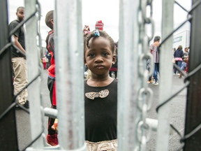 A girl who crossed the Canadian border illegally with her family to seek refugee status, looks through a fence at a temporary detention centre in Blackpool, Quebec.