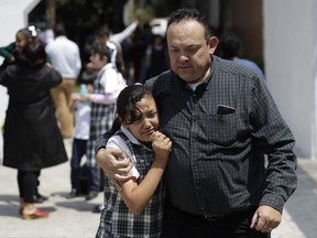 A man comforts a frightened student as he collects her from her school in the Roma neighborhood of Mexico City, after an earthquake, Tuesday, Sept. 19, 2017. A 7.1 earthquake stunned central Mexico, killing more than 100 people as buildings collapsed in plumes of dust.(AP Photo/Rebecca Blackwell)
