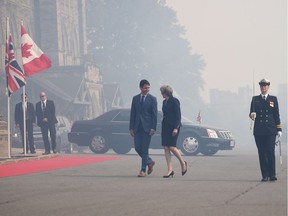 The air is filled by cannon smoke as British Prime Minister Theresa May is greeted by Prime Minister Justin Trudeau as she arrives to Parliament Hill in Ottawa on Monday, Sept. 18, 2017.