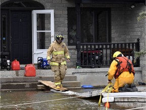 An Ottawa firefighter crosses a makeshift bridge to help residents who remained in their homes in Cumberland