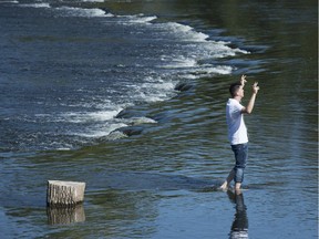 Adam Campbell dances as listens to music while cooling himself in the Rideau River Monday