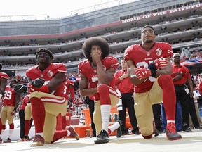 In this Oct. 2, 2016, file photo, from left, San Francisco 49ers outside linebacker Eli Harold, quarterback Colin Kaepernick, center, and safety Eric Reid kneel during the national anthem before an NFL football game against the Dallas Cowboys in Santa Clara, Calif.