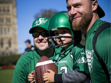 The Saskatchewan Roughriders held a practice on Parliament Hill Sunday October 1, 2017 in Ottawa, after playing the Redblacks Friday night. L-R Matt Dingle, four-year-old Declan Dingle and Rob Bagg pose for a photo.   Ashley Fraser/Postmedia