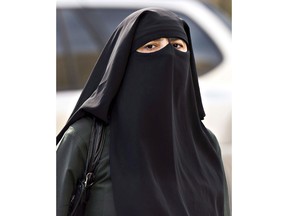 A woman wears a niqab as she walks Monday, September 9, 2013 in Montreal. The Quebec national assembly has passed a controversial religious neutrality bill that obliges citizens to uncover their faces while giving and receiving state services.