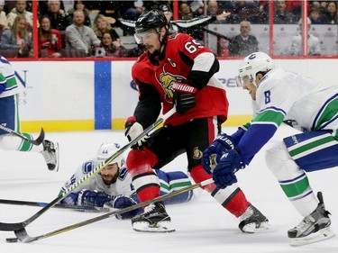 Ottawa's captain Erik Karlsson (centre) gets past Vancouver to bring the puck to the net during first-period action between the Ottawa Senators (red) and the Vancouver Canucks Tuesday (October 17, 2017) at Canadian Tire Centre.