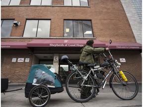 A man pushes a loaded bike in front of the Shepherds of Good Hope.