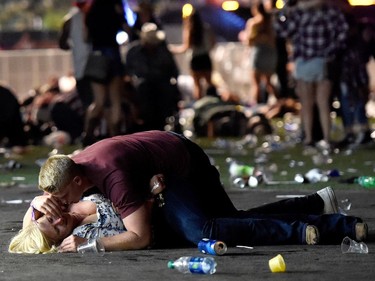 A man lays on top of a woman as others flee the Route 91 Harvest country music festival grounds after a active shooter was reported on October 1, 2017 in Las Vegas, Nevada. A gunman has opened fire on a music festival in Las Vegas, leaving at least 2 people dead. Police have confirmed that one suspect has been shot. The investigation is ongoing.