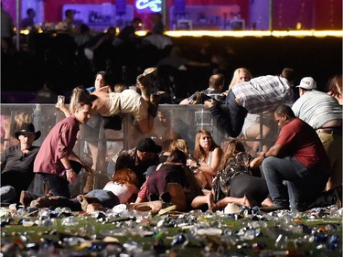 People scramble for shelter at the Route 91 Harvest country music festival after apparent gun fire was heard on October 1, 2017 in Las Vegas, Nevada. A gunman has opened fire on a music festival in Las Vegas, leaving at least 20 people dead and more than 100 injured. Police have confirmed that one suspect has been shot. The investigation is ongoing.