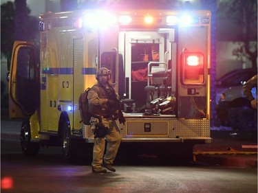 Las Vegas Metropolitan Police Department officers stand near an ambulance as medical personnel treat a person in the parking lot of the Hooters Casino Hotel after a mass shooting at a country music festival nearby on October 1, 2017 in Las Vegas, Nevada.   A gunman has opened fire on a music festival in Las Vegas, leaving at least 20 people dead and more than 100 injured. Police have confirmed that one suspect has been shot. The investigation is ongoing.