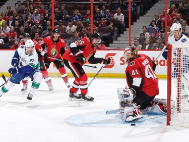 Craig Anderson #41 of the Ottawa Senators makes a pad save against Ben Hutton #27 of the Vancouver Canucks as Erik Karlsson #65 of the Ottawa Senators and Daniel Sedin #22 of the Vancouver Canucks look on in the first period at Canadian Tire Centre on October 17, 2017 in Ottawa, Ontario, Canada.  (Photo by Jana Chytilova/Freestyle Photography/Getty Images)