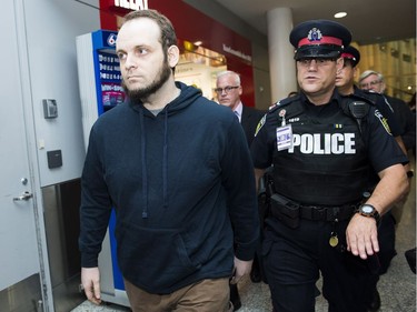 Joshua Boyle, left, gets a police escort after speaking to the media after arriving at the airport in Toronto on Friday, October 13, 2017.
