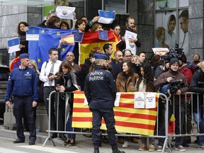 Police stand in front of people holding Catalan, Spanish and European flags during demonstrations over Catalan independence in front of the Press Club in Brussels on Tuesday.
