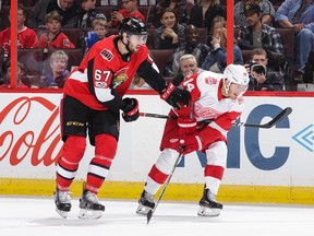 Ben Harpur of the Senators has his stick held by Gustav Nyquist of the Red Wings in the first period of Saturday's game. Harpur later left the contest because of an upper-body injury.