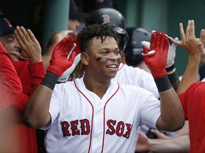 Boston Red Sox's Rafael Devers, center, is congratulated by teammates in the dugout after his two-run home run against the Houston Astros during the third inning in Game 3 of baseball's American League Division Series, Sunday, Oct. 8, 2017, in Boston. (AP Photo/Michael Dwyer)