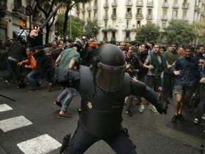 Spanish riot police swings a club against would-be voters near a school assigned to be a polling station by the Catalan government in Barcelona, Spain, Sunday, Oct. 1, 2017.