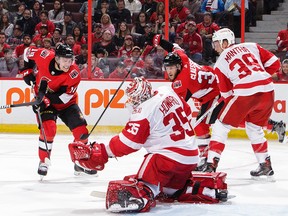 Jimmy Howard of the Red Wings makes a glove save against Ryan Dzingel of the Senators as Fredrik Claesson and Anthony Mantha look on in the second period of Saturday's contest.