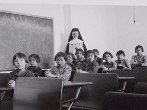 Group of female students and a nun in a classroom at Cross Lake Indian Residential School, Cross Lake, Manitoba, February 1940.