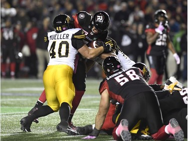 Tiger-Cats defensive end Ryan Mueller (40) and defensive back Courtney Stephen (22) tackle Redblacks quarterback Trevor Harris on a first-half quarterback sneak. Harris was injured on the play, but returned to the field shortly after that. THE CANADIAN PRESS/Justin Tang