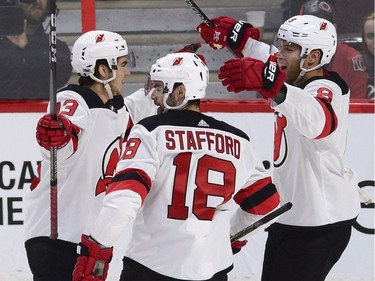 The New Jersey Devils' Nico Hischier, left, celebrates one of his goals against the Ottawa Senators with teammates Drew Stafford (18) and Taylor Hall (9).