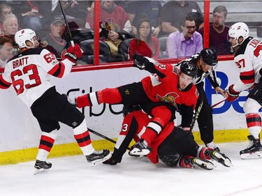 The Senators' Mark Stone trips over teammate Fredrik Claesson between the Devils' Jesper Bratt, left, and centre Pavel Zacha.