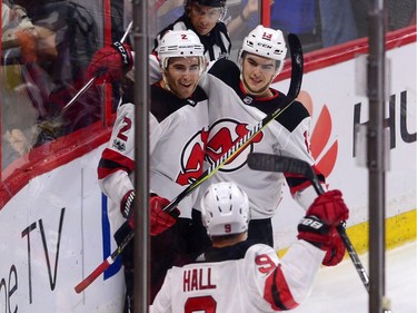 New Jersey Devils defenceman John Moore, left, celebrates his game-winning overtime goal against the Ottawa Senators with teammates Nico Hischier, right, and Taylor Hall.