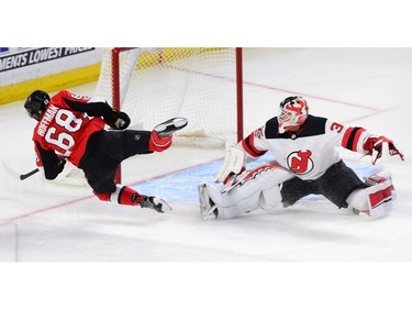 The Senators' Mike Hoffman flies through the air as he attempts to score on New Jersey Devils goalie Cory Schneider.