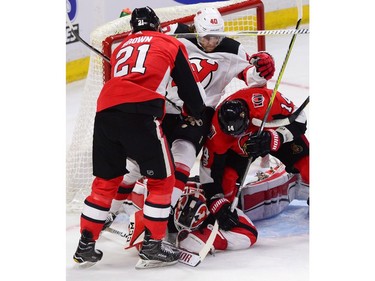 New Jersey Devils centre Blake Coleman is knocked down as goalie Cory Schneider dives on the puck while Ottawa Senators centre Logan Brown (21) and right wing Alex Burrows (14) look for a rebound.