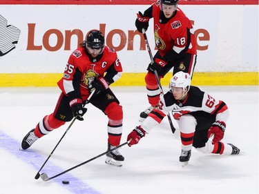 Ottawa Senators defenceman Erik Karlsson fights for the puck against New Jersey Devils left wing Jesper Bratt.