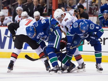 Vancouver Canucks' Brandon Sutter (20) and teammate Chris Tanev (8) vie for control of the puck with Ottawa Senators' Kyle Turris (7) and teammate Dion Phaneuf during first period NHL hockey action in Vancouver on Tuesday, October 10, 2017.