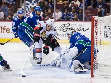 Ottawa Senators' Mark Borowiecki (74) loses control of the puck in front of Vancouver Canucks goalie Jacob Markstrom, of Sweden, as Erik Gudbranson (44) watches during first period NHL hockey action in Vancouver on Tuesday, October 10, 2017.