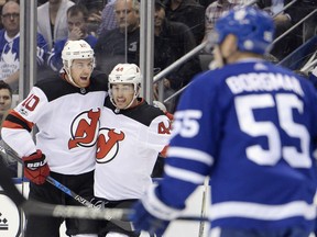 Miles Wood, right, celebrates his goal with Devils teammate Jimmy Hayes as Maple Leafs defenceman Andreas Borgman looks on during first period NHL action in Toronto on Wednesday night.