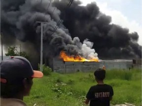 In this image made from video, residents watch as thick black smoke billows from the site of an explosion at a firecracker factory in Tangerang, on the outskirt of Jakarta, Indonesia, Thursday, Oct. 26, 2017. The explosion and raging fire killed a number of people and injured dozens, police said. (AP Photo) ORG XMIT: JAK108

IMAGE MADE FROM VIDEO
AP