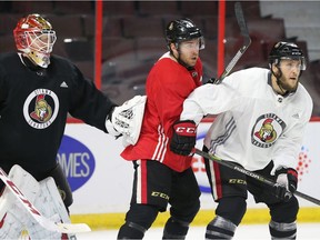 Senators forward Chris DiDomenico, middle, and defenceman Fredrik Claesson battle for position in front of netminder Mike Condon during Senators practice on Monday. Jean Levac/Postmedia