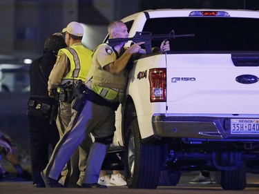 A police officer takes cover behind a truck at the scene of a shooting near the Mandalay Bay resort and casino on the Las Vegas Strip, Sunday, Oct. 1, 2017, in Las Vegas. Multiple victims were being transported to hospitals after a shooting late Sunday at a music festival on the Las Vegas Strip.