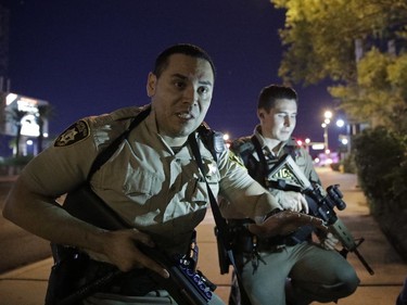 Police officers advise people to take cover near the scene of a shooting near the Mandalay Bay resort and casino on the Las Vegas Strip, Sunday, Oct. 1, 2017, in Las Vegas.