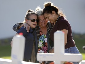 mourners embrace as they look at crosses planted in honour of those killed in the mass shooting Friday, Oct. 6, 2017, in Las Vegas.