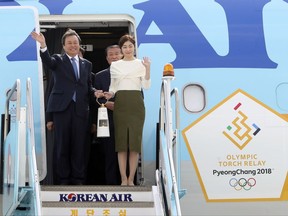 South Korean Minister of Culture, Sports and Tourism Do Jong-whan, left, and former South Korean Olympic figure skating champion Yuna Kim, hold the Olympic flame upon arrival at Incheon International Airport in Incheon, South Korea, Wednesday, Nov. 1, 2017. (AP Photo/Lee Jin-man)